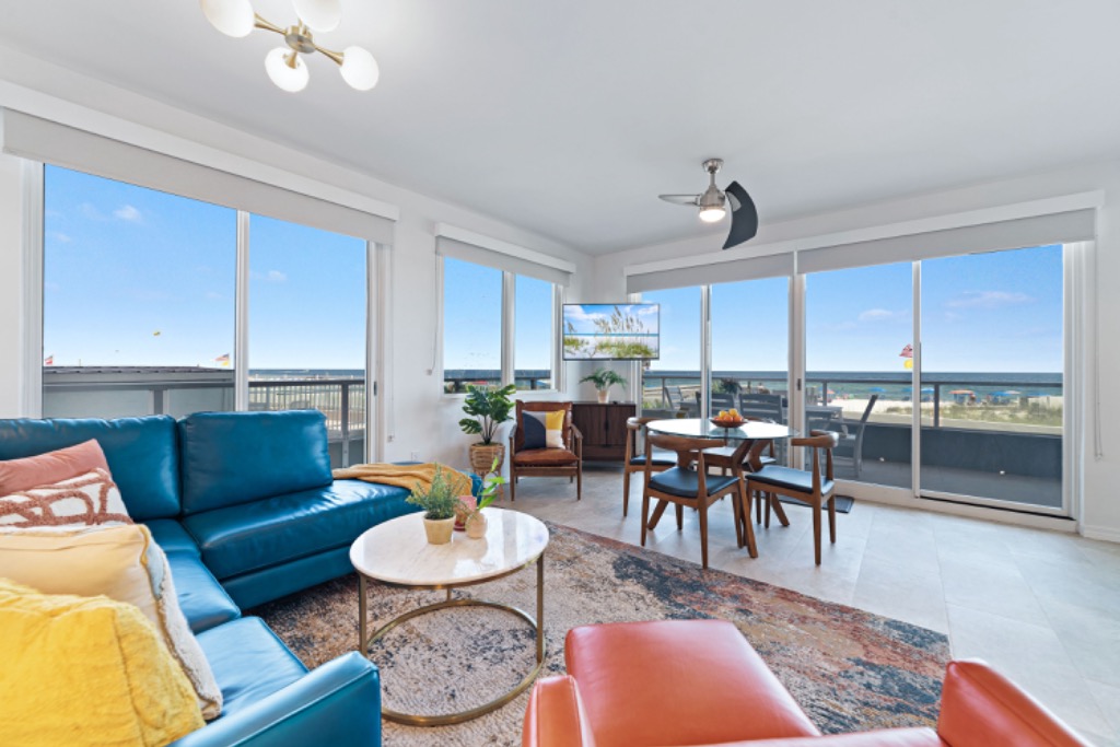 Living room with teal leather sectional and floor-to-ceiling Gulf views
