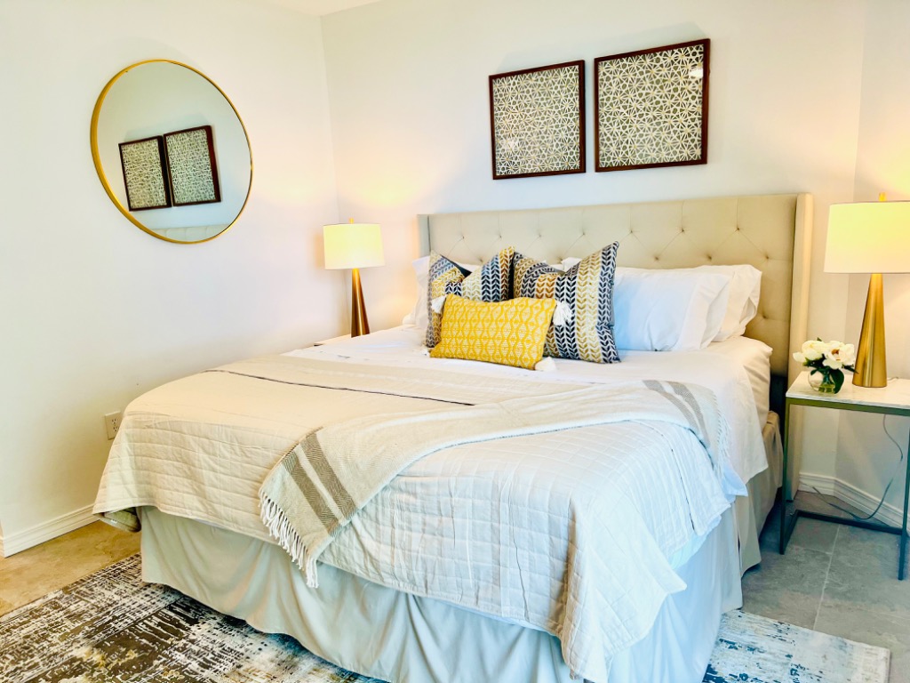 Primary bedroom with king bed, tufted headboard, and brass mirror